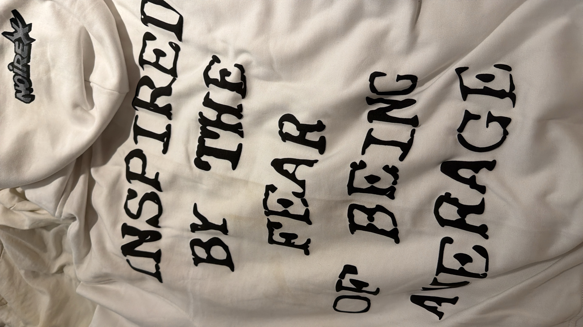 NOIREX hoodie flat lay showing back text — Inspired by the fear of being average